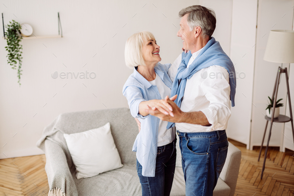 Happy mature couple dancing in the living room