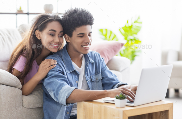 Happy African Teen Couple Working Together On Laptop At Home Stock Photo By Prostock Studio
