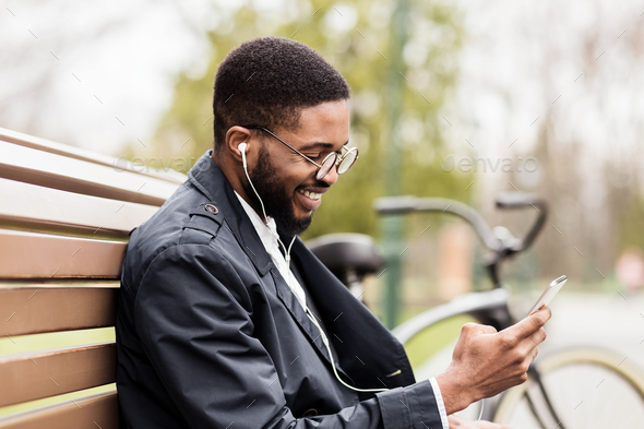 Happy Afro Man Sitting In Park And Listening Music Stock Photo By Prostock Studio photodune