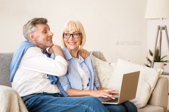 Happy senior couple websurfing on laptop at home - Stock Photo - Images