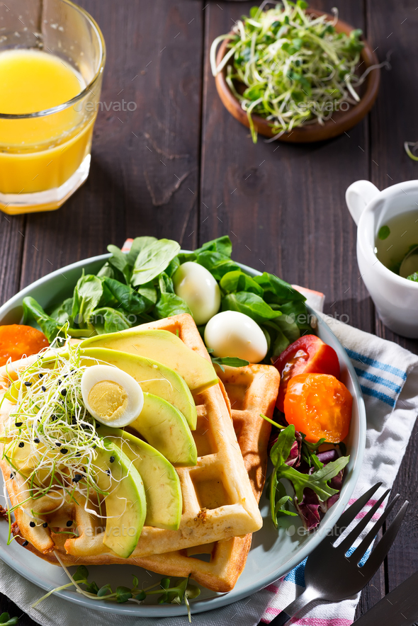 Belgian Waffles with avocado, eggs, micro green and tomatoes with orange juice on marble table - Stock Photo - Images