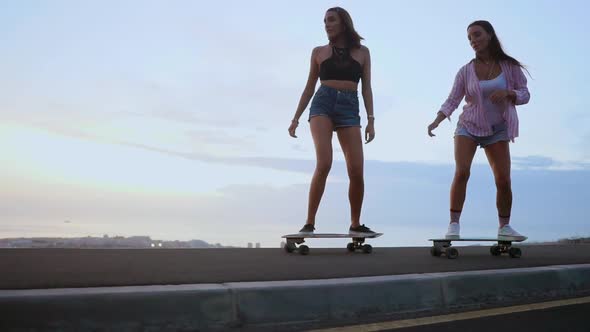 Two Girls Skateboarder Rides on a Board on the Slope Against the Sky From the Mountain. Slow Motion alt