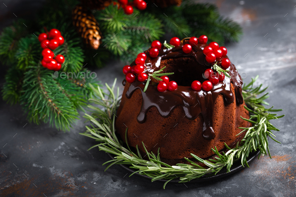 Christmas chocolate bundt cake with glaze decorated with fresh berries and rosemary - Stock Photo - Images
