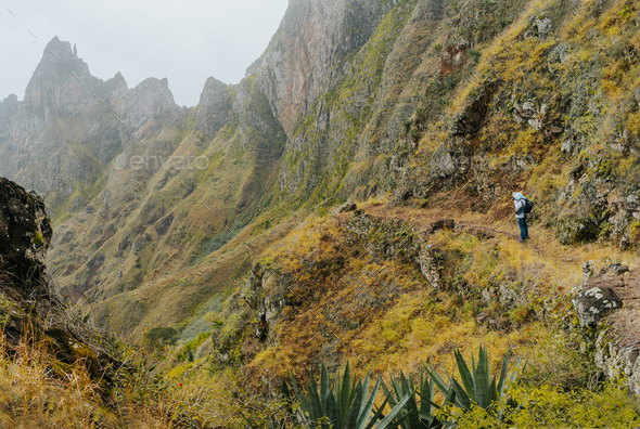 Traveler with camera in front of the monumental mountain ridge and ravine on the cobbled path to Xo - Stock Photo - Images