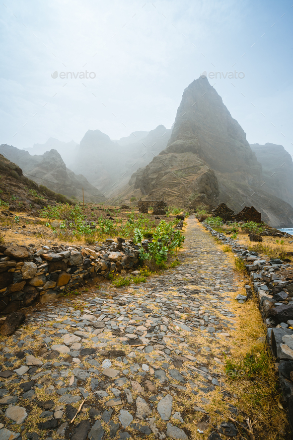 Aranhas mountain peak in the valley with house ruins and stony hiking path going up the mountain - Stock Photo - Images