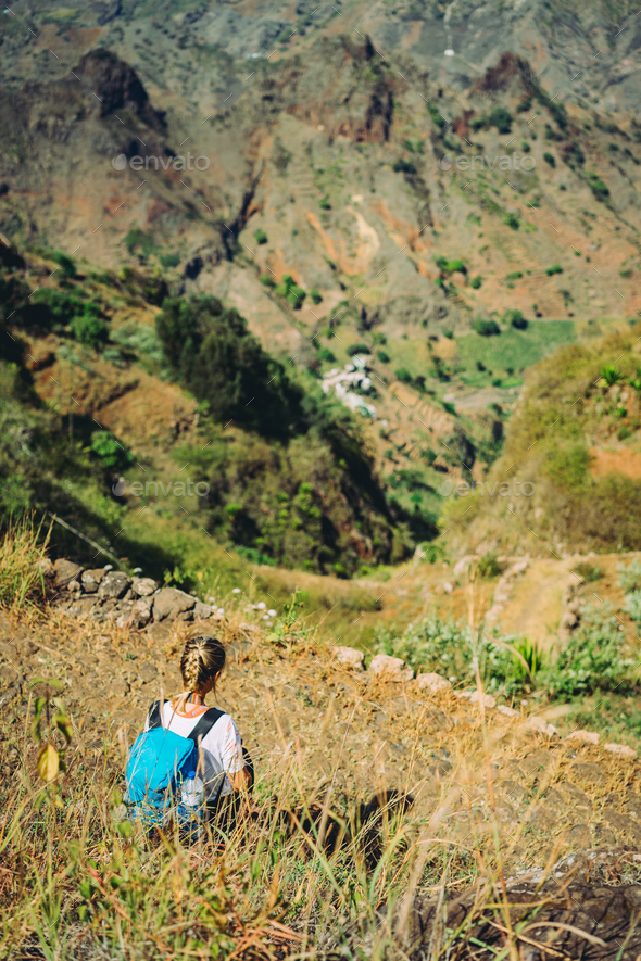 Hiker woman take a rest on mountain slope. Sitting on sharp summit and enjoy spectacular view - Stock Photo - Images