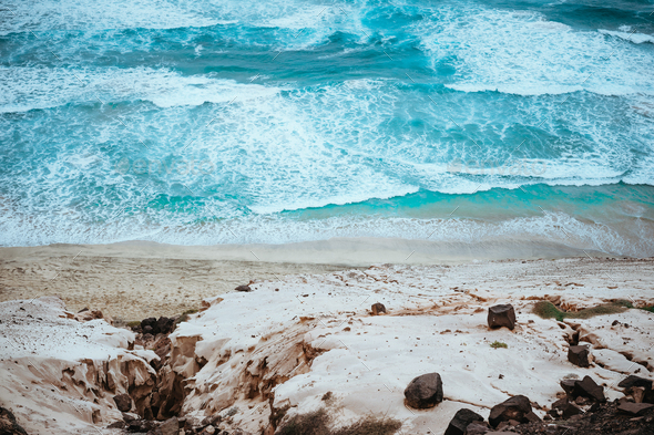 Quaint view of azure roaring ocean, black volcanic stones and massive sand dunes along the coast - Stock Photo - Images