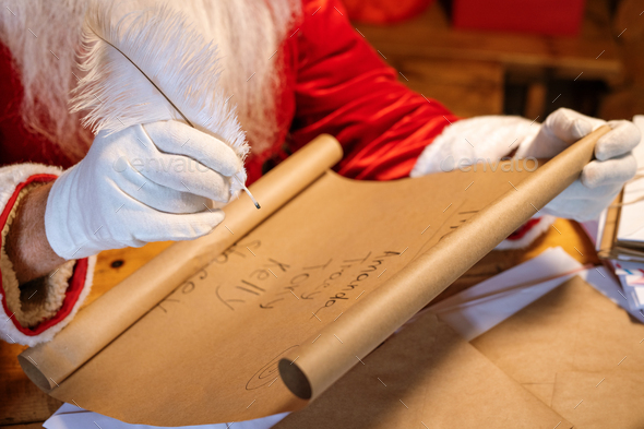 Gloved Santa holding pen over big paper with list of kids names - Stock Photo - Images