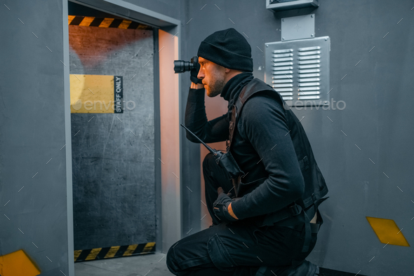 Male robber in black uniform holds gun and lantern