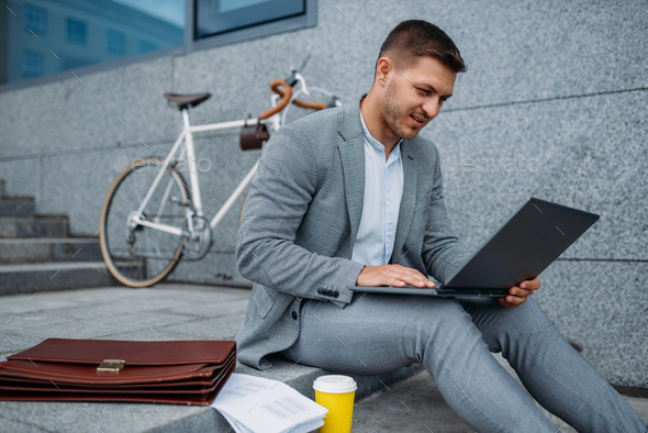 Businessman with bike and laptop having lunch