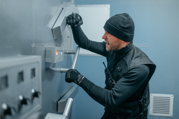 Robbers in black uniform trying to open vault lock