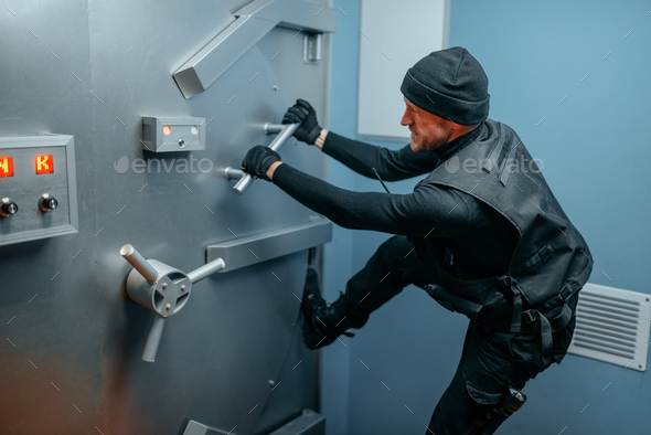 Robber in black uniform trying to break vault lock