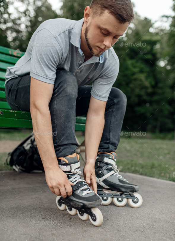 Roller skating, male skater puts on skates in park - Stock Photo - Images