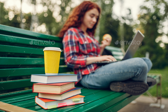 Female student having lunch on the bench in park - Stock Photo - Images