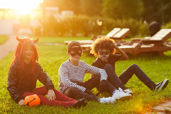 Friends Sitting on Grass on Halloween Day - Stock Photo - Images