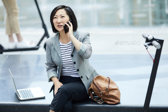 Asian Woman Speaking by Smartphone in City - Stock Photo - Images