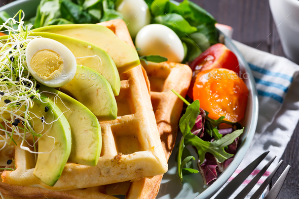 Belgian Waffles with avocado, eggs, micro green and tomatoes with orange juice close-up. Perfect