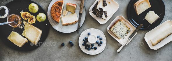Variety of snacks and cheeses over grey background, wide composition - Stock Photo - Images