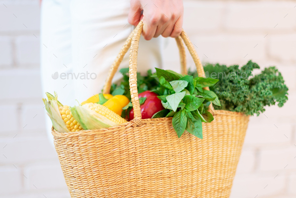 Zero waste concept with copy space. Woman holding straw basket with vegetables, products. Eco - Stock Photo - Images