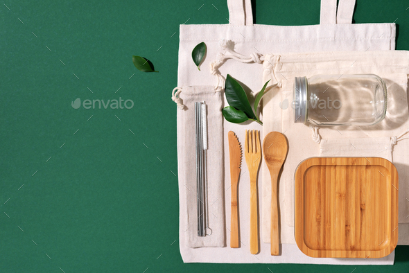 Cotton bags, glass jar, bottle, metal cup, straws for drinking, bamboo cutlery and boxes on green - Stock Photo - Images