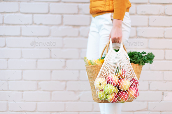 Zero waste concept with copy space. Woman holding straw basket and reusable mesh shopping bag - Stock Photo - Images
