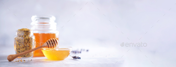 Honey products background. Honeycomb frame, bee pollen granules, honey in glass pot on grey concrete - Stock Photo - Images