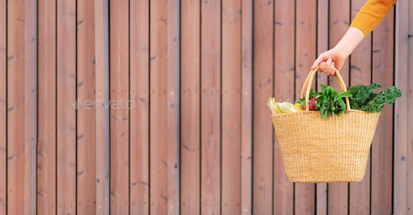 Girl holding basket with healthy organic vegetables, wooden background, copy space. Autumn harvest - Stock Photo - Images