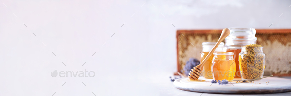 Honey products background. Honeycomb frame, bee pollen granules, honey in glass pot on grey concrete - Stock Photo - Images