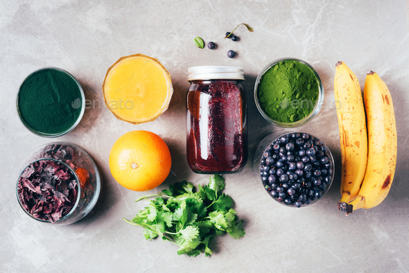 Blueberries, bilberry, barley grass, spirulina, orange juice, dulse, cilantro on marble background - Stock Photo - Images