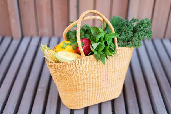 Girl holding basket with healthy organic vegetables, wooden background, copy space. Autumn harvest - Stock Photo - Images