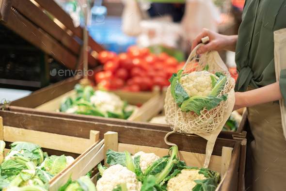 Girl holding mesh shopping bag and cotton shopper with vegetables without plastic bags, wooden - Stock Photo - Images