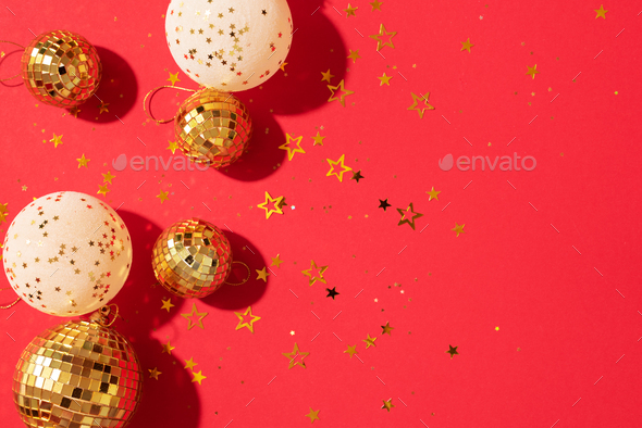 Creative Christmas concept. Shiny gold disco balls over red background.  Flat lay, top view. New year Stock Photo by jchizhe