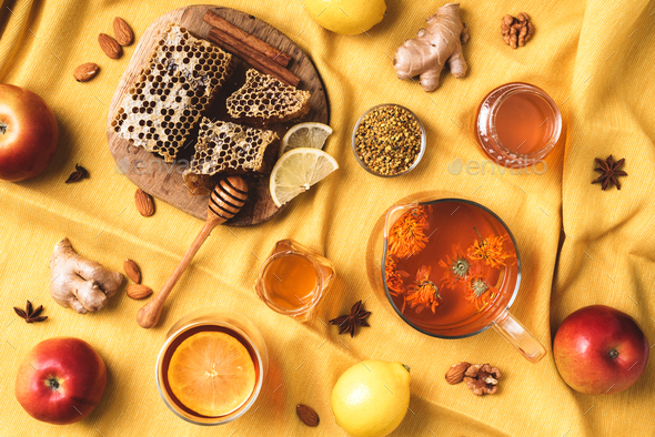 Autumn harvest concept. Set of honey and bee products, apple, lemon, calendula tea, spices on yellow - Stock Photo - Images