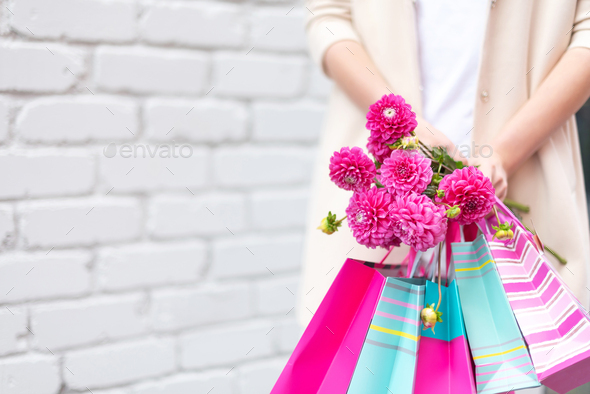 Pink flowers in female hands and shopping bags on brick background. Birthday, Mother's, Women - Stock Photo - Images