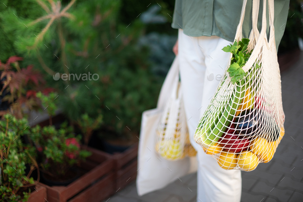 Girl holding mesh shopping bag and cotton shopper with vegetables without plastic bags at farmers - Stock Photo - Images