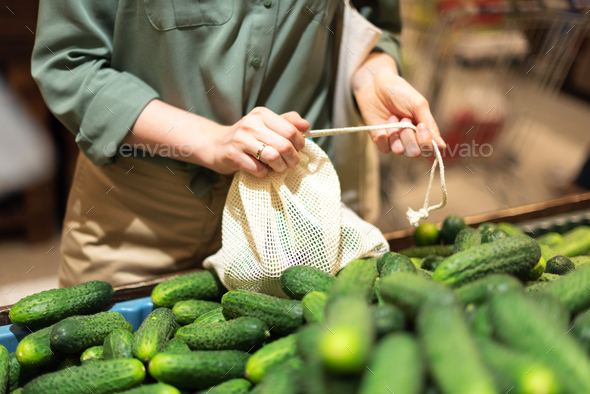 Woman chooses cucumbers at farmers market. Zero waste, plastic free concept. Sustainable lifestyle