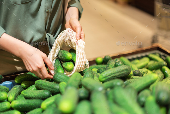 Woman chooses cucumbers at farmers market. Zero waste, plastic free concept. Sustainable lifestyle