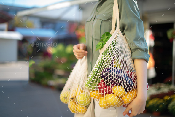 Girl holding mesh shopping bag and cotton shopper with vegetables without plastic bags at farmers - Stock Photo - Images