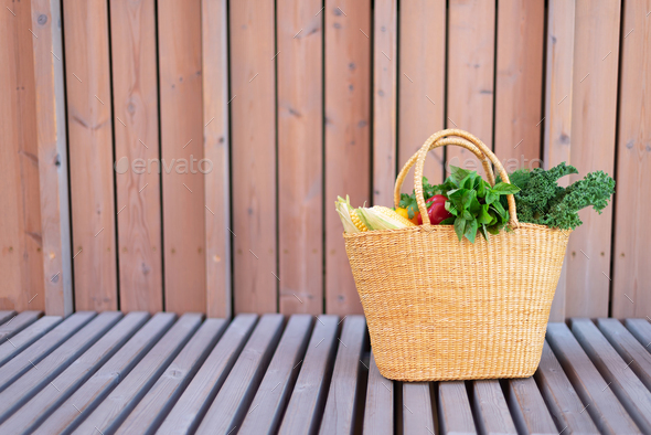Girl holding basket with healthy organic vegetables, wooden background, copy space. Autumn harvest - Stock Photo - Images