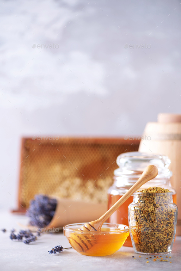 Honey products background. Honeycomb frame, bee pollen granules, honey in glass pot on grey concrete - Stock Photo - Images