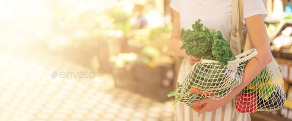 Girl holding mesh shopping bag and cotton shopper with vegetables without plastic bags, wooden - Stock Photo - Images