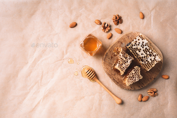 Bee pollen granules, honey jar with wooden dropper, honeycomb and almond nuts on craft paper - Stock Photo - Images