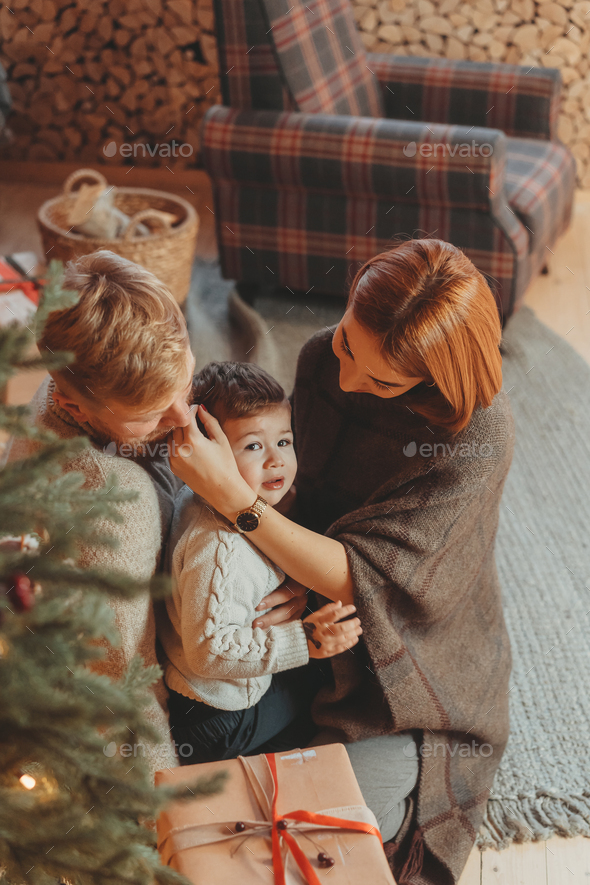 Young caucasian family mom dad son near fireplace christmas tree - Stock Photo - Images