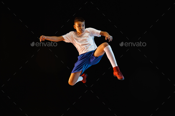 Young boy as a soccer or football player on dark studio background - Stock Photo - Images