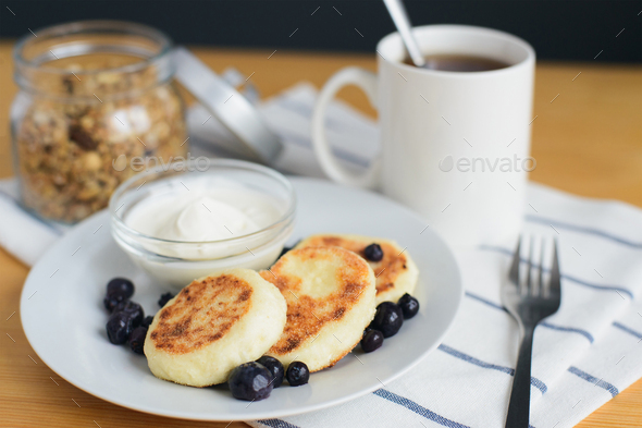 fried circular syrniki, tvorozhniki or cheese cake with sour cream and hot drink - Stock Photo - Images