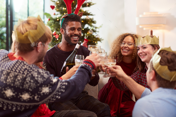 Group Of Friends Celebrating With Champagne After Enjoying Christmas Dinner At Home