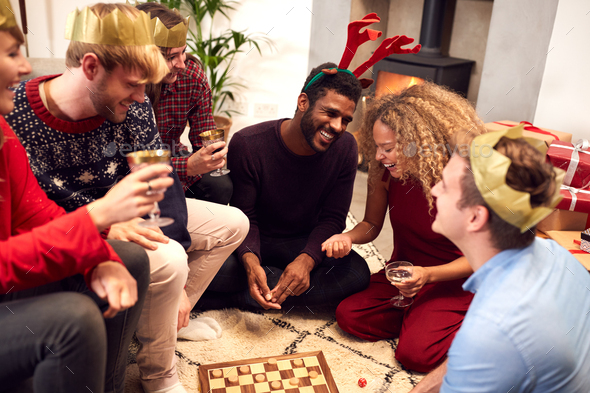 Group Of Friends Playing Board Games After Enjoying Christmas Dinner At Home