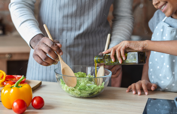 Little girl adding olive oil to healthy veggies salad - Stock Photo - Images