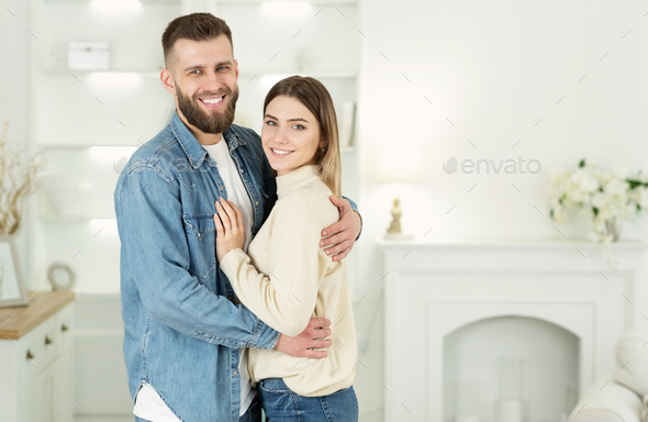 Renting flat. Young family embracing and smiling to camera