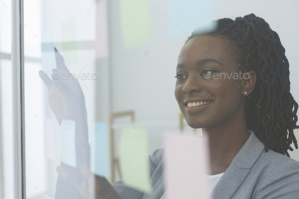 Afro Lady Putting Sticky Notes On Glass Board At Workplace